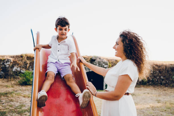 istock Boy on slide with mom by her side 2173984447