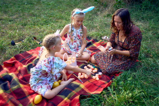 istock two little girls and mom paint eggs at easter picnic 2173992436