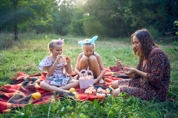 istock two little girls and mom paint eggs at easter picnic 2173992445