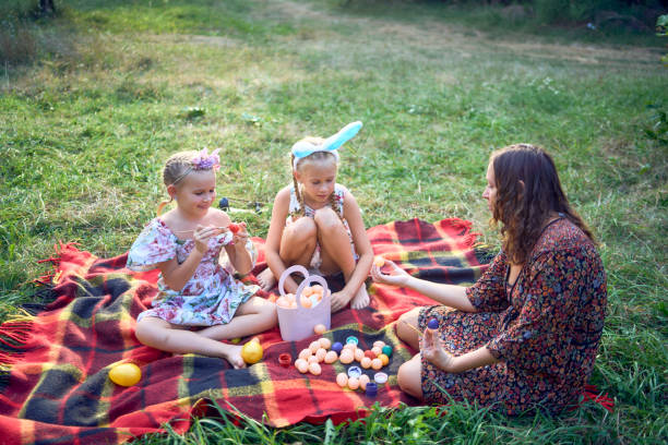istock two little girls and mom paint eggs at easter picnic 2173992758