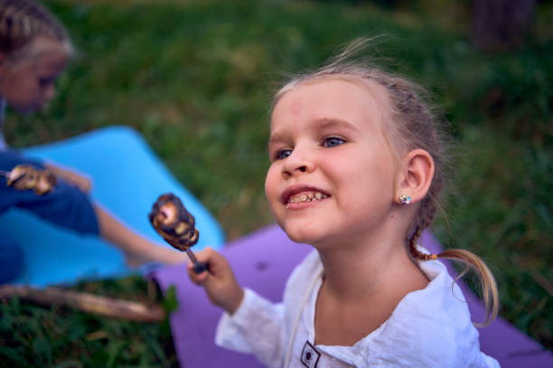 mother and her daughters  roasting and eating marshmallows on the campfire, camping vacation with children