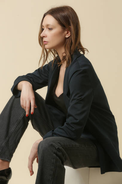 Female model wearing black shirt, jeans and dark blue blazer. Studio shoot.