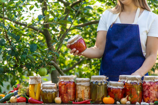 istock woman canning tomatoes cucumbers vegetables on the background of nature. Selective focus 2173998564