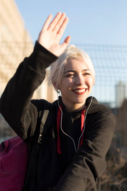 Joyful young woman waving in the sunlight
