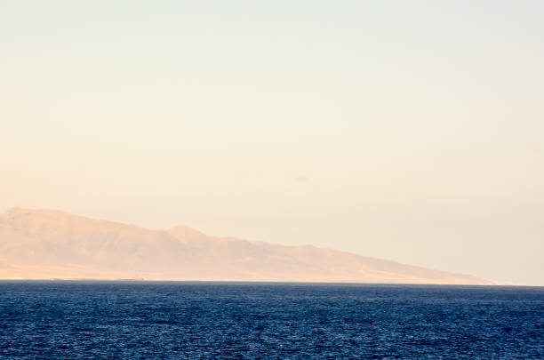 istock A calm ocean with a mountain in the background 2174000065