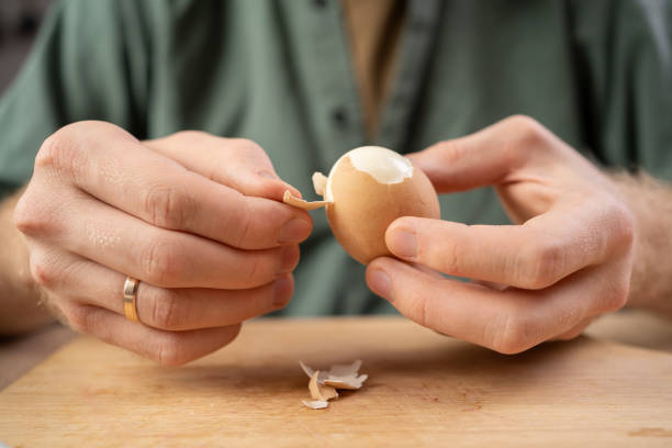 istock Man peeling boiled egg on wooden table on the kitchen 2174000184