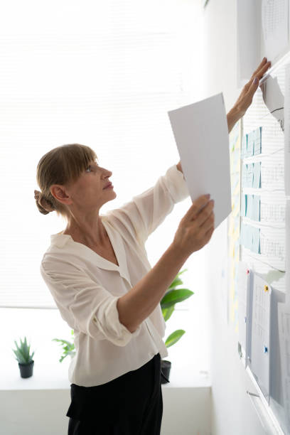 istock Senior businesswoman organizing documents on office wall 2174000224