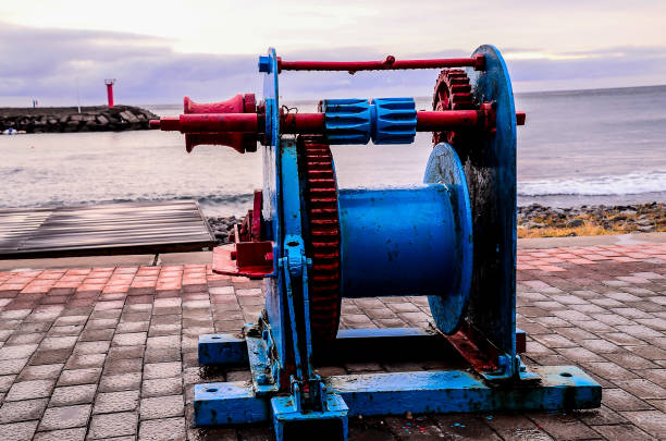 A blue and red rope is on the ground next to the water. The rope is old and rusty