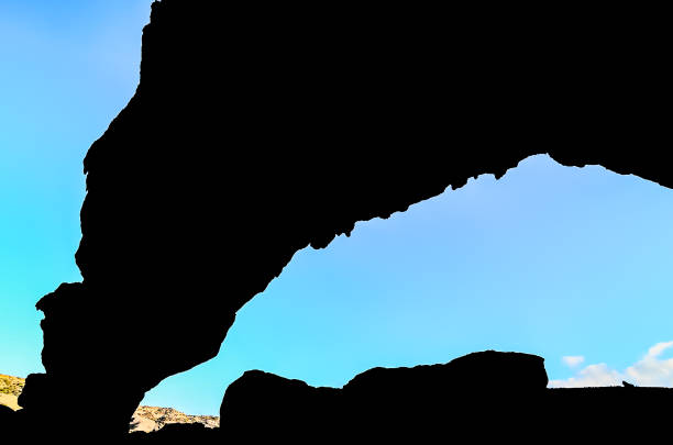 A large rock formation with a blue sky in the background. The sky is clear and the sun is shining brightly