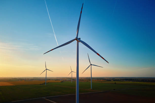 Silhouetted wind turbines in countryside landscape during sunset