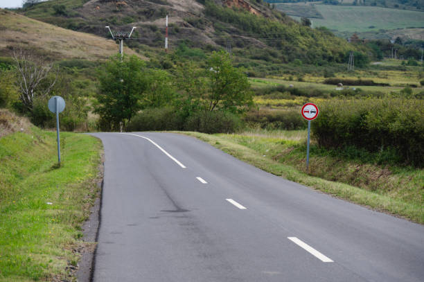 istock Empty country road winding through green trees and hills 2174001797