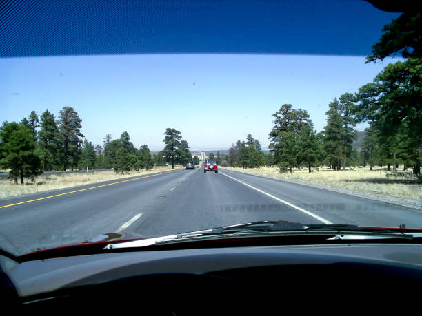 The dashboard and steering wheel looking out the front window of a car heading down an American Freeway on a Clear day through the desert