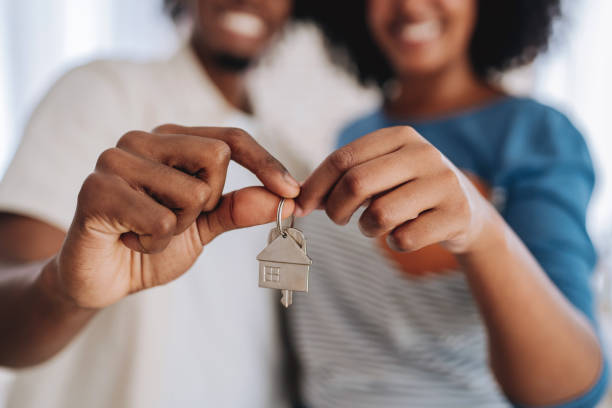 Happy couple buys a house and holds the keys while smiling stock photo
