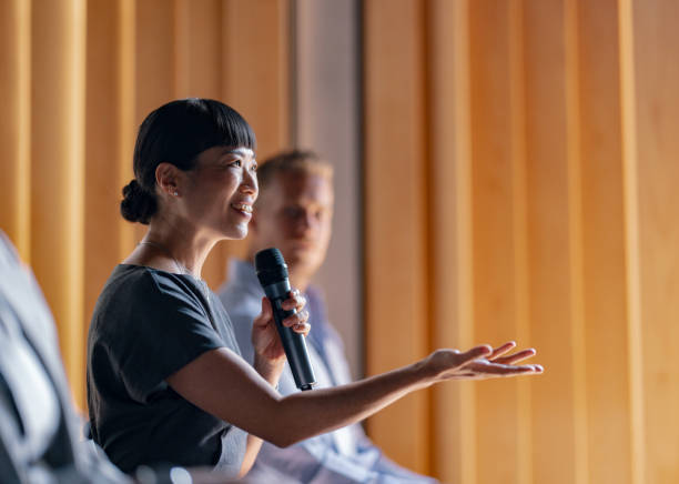 A professional woman giving a speech at a business event, engaging the audience with her presentation. Captures the essence of effective communication and leadership.