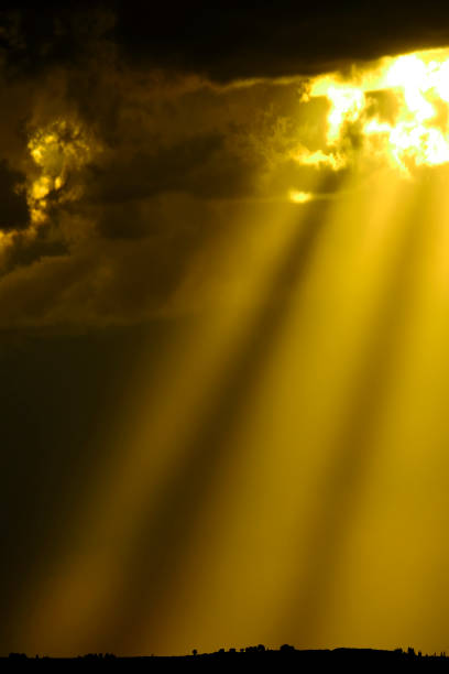 istock Golden Warm Sun Beams from a Stormy Sky Shining Down 2174031394
