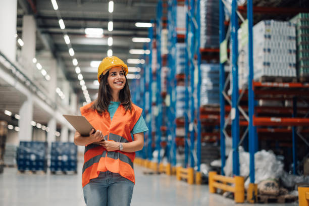 istock Woman warehouse inspector smiling with clipboard under bright lights 2174040310