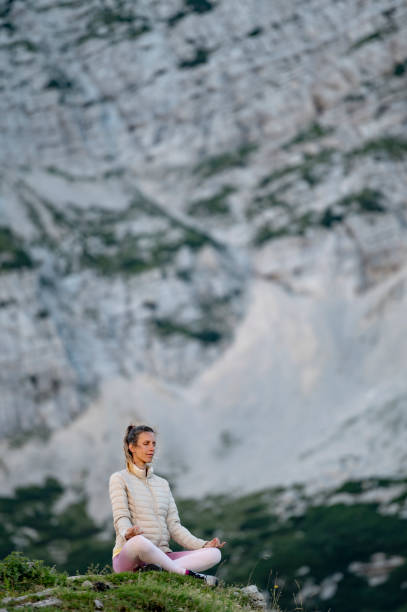 istock Young woman meditating on a rock in high mountains 2174040689