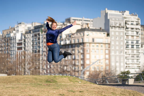 istock Woman celebrating, jumping for joy in a park 2174041658