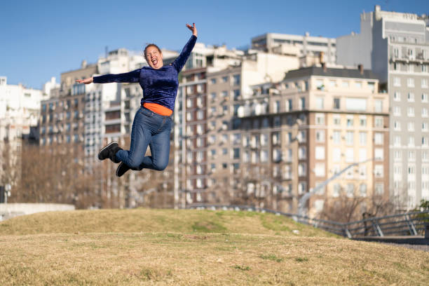 istock Woman celebrating, jumping for joy in a park 2174041660