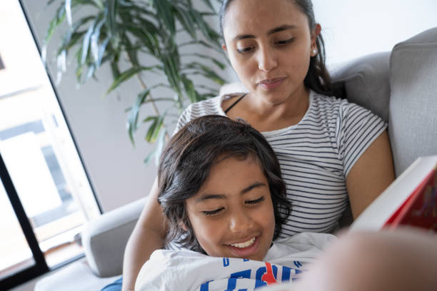 istock Son with his mom at home reading a book without technology or electronic devices inside her home during the day 2174042178