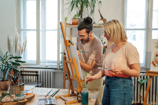 istock Happy artists in creative studio painting together on canvas. 2174042713