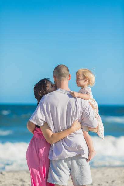 istock Happy parents carrying little doughter at beach 2174059550