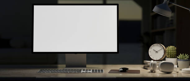 istock A computer with a white screen mockup and accessories on a desk in a room at night. 2174060170
