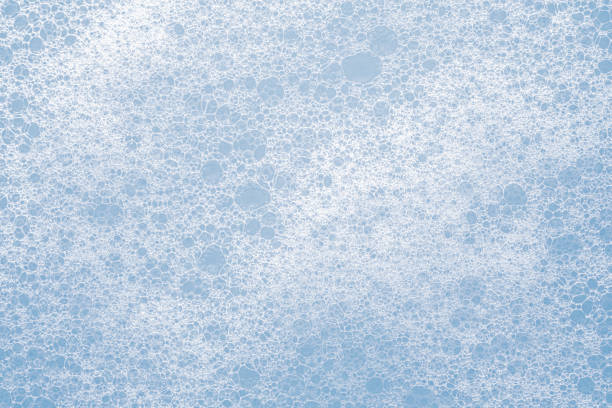 Close-up view of soap bubbles on a light blue background creating abstract patterns.
