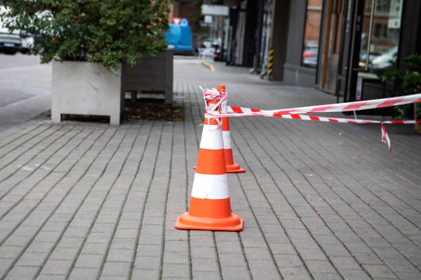 istock Two orange and white warning cones and demarcation tape on the pavement 2174066017