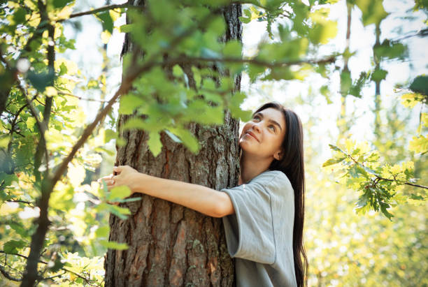 istock Young woman embracing a tree while enjoying nature in a sunlit forest during summer 2174079057