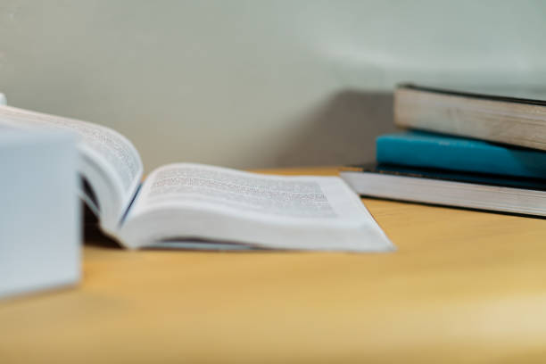 Open book and stacked notebooks on a wooden desk, representing study, learning, and academic concepts. Ideal for educational themes and productivity.
