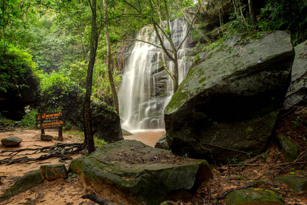 istock Waterfall. Woman standing with arms spread out looking at the waterfall. 2174083499