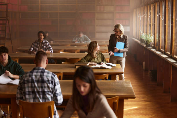 istock Senior professor talking to her student on a class in library. 2174084574