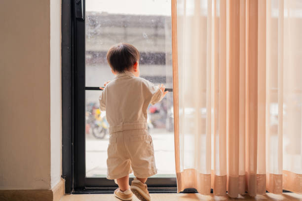 asian curious Baby Looking Out through the net curtains. Back view