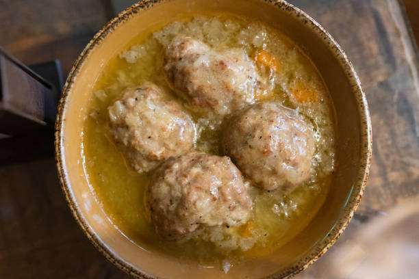 Four large meatballs in a rich chicken broth served in large ceramic bowl.