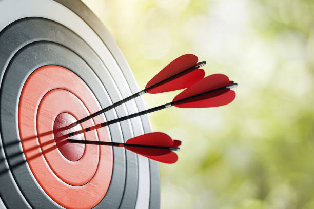 istock Three red darts hitting the bullseye on a dartboard outdoors. 3D Rendering 2174090932
