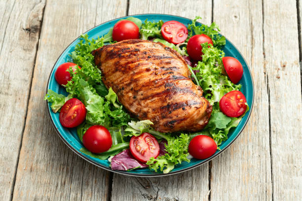 istock Grilled chicken breast ( fillet ) with lattuce salad and cherry tomatoes . Top view 2174096818