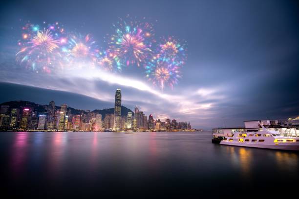 istock A cityscape with skyscrapers illuminated at night. Colorful fireworks explode in the sky above the city. A boat travels across a still body of water. 2174098275