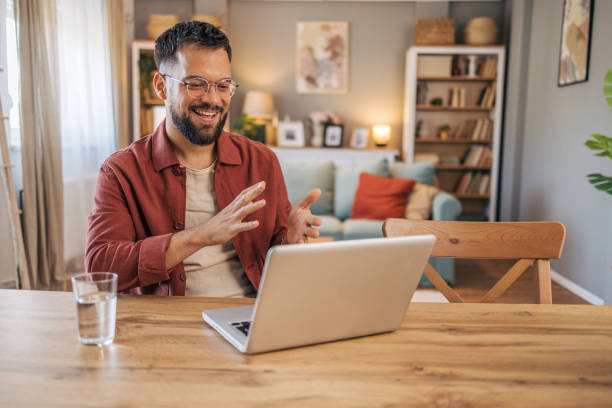 istock A mid adult handsome man using her laptop for video call. 2174103678