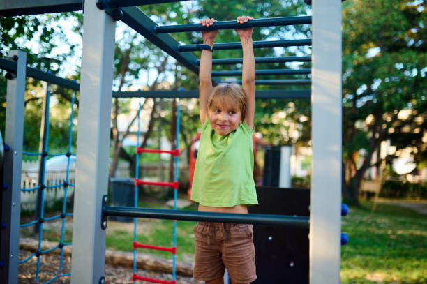 istock A child climbs confidently on playground equipment under a clear sky surrounded by greenery during a sunny afternoon 2174103925