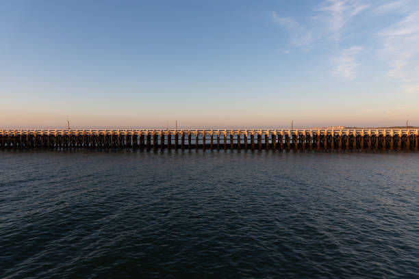 Wooden pier in the North Sea with blue sky on the background during sunset