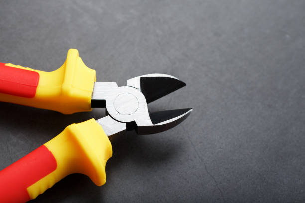 Pliers are a cutting tool with a red handle on a black background. Free space, top view