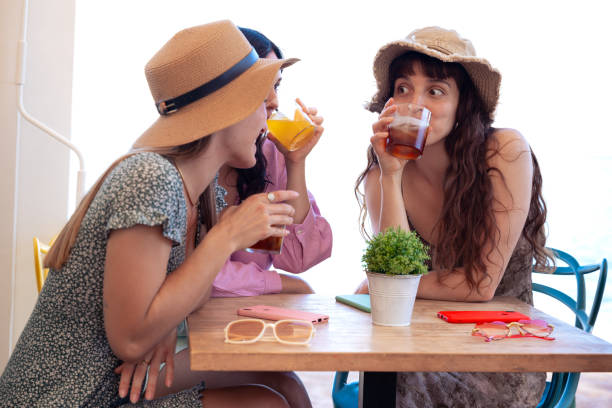 istock Three young friends in summer dresses having a soft drink in a restaurant 2174114164