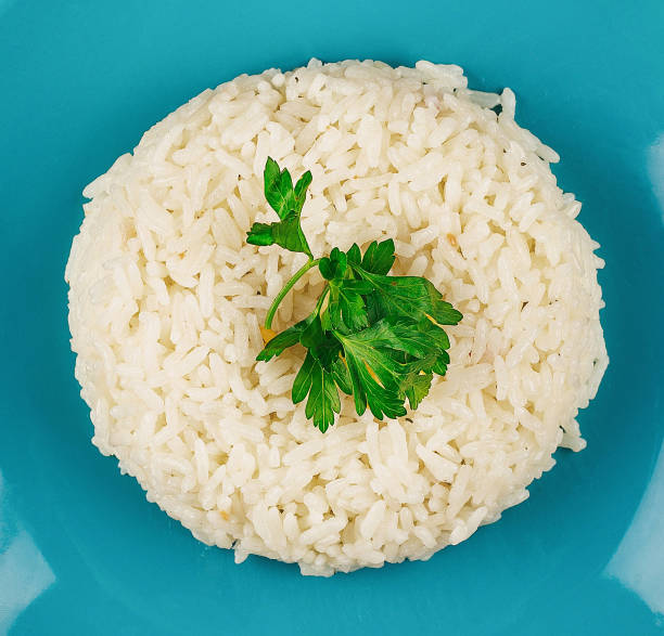istock Steamed white rice lying on blue plate with parsley garnish 2174116635