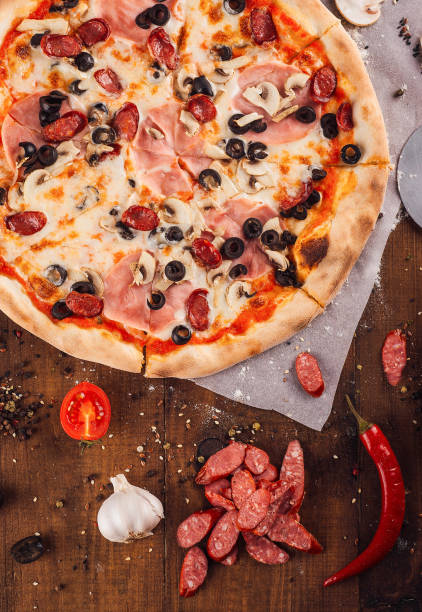 istock Delicious pizza lying on wooden table surrounded by fresh ingredients 2174117085