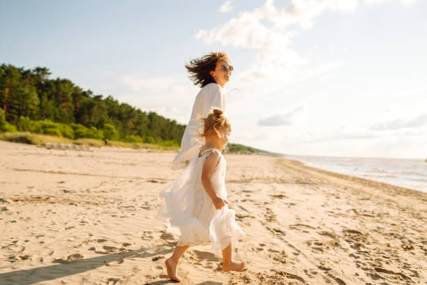 istock A mother and daughter enjoy a sunny beach stroll. 2174119714