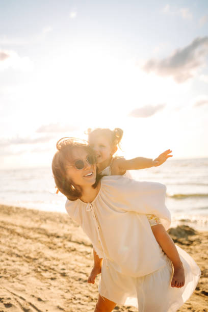 istock A mother and daughter enjoy a sunny beach stroll. 2174119755