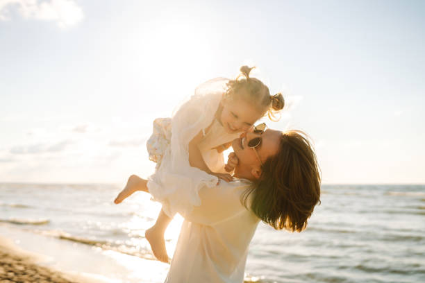 istock A mother and daughter enjoy a sunny beach stroll. 2174119762