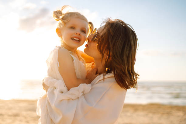 istock A mother and daughter enjoy a sunny beach stroll. 2174119765
