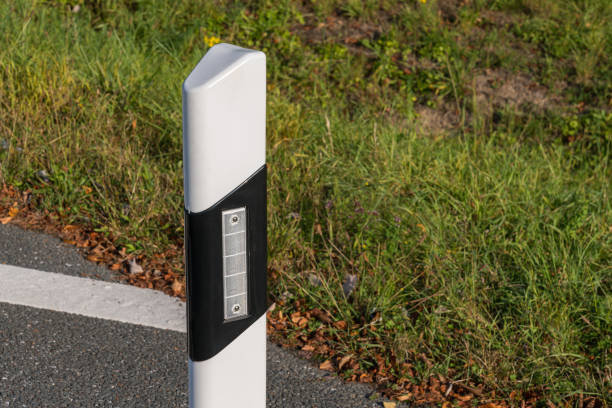 istock A white reflective road marker stands beside a paved pathway in a rural area. 2174122610